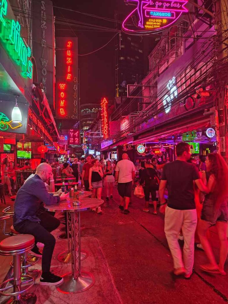 People walking through Soi Cowboy red light district in Bangkok Thailand at night