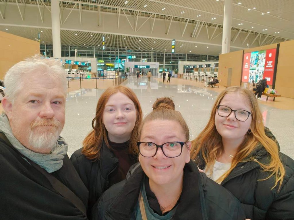 Mark Bec and their two adult daughters at the airport before a trip β the kids are now grown up and starting their own lives in Australia